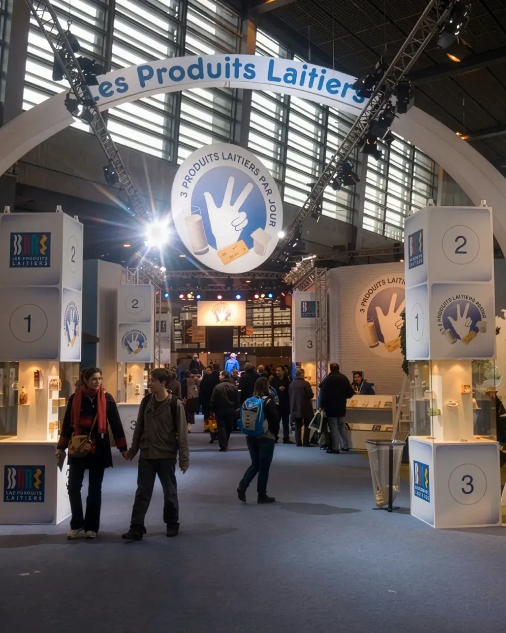 Stand ouvert avec grandes colonnes intégrant des vitrines et une enseigne haute ronde Les Produits Laitiers.